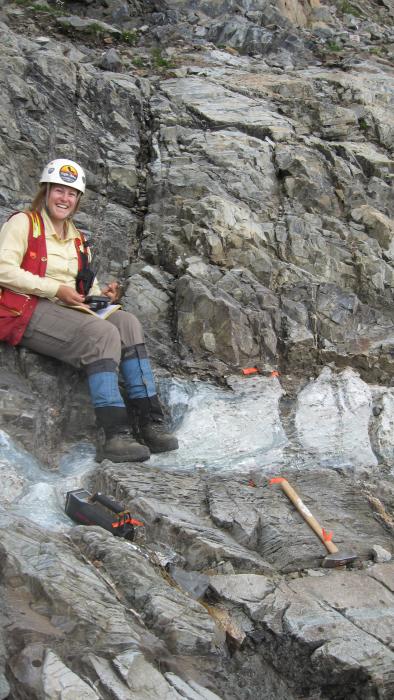 A geologist sampling a carbonitite dike on a steep face at the Ice river Complex